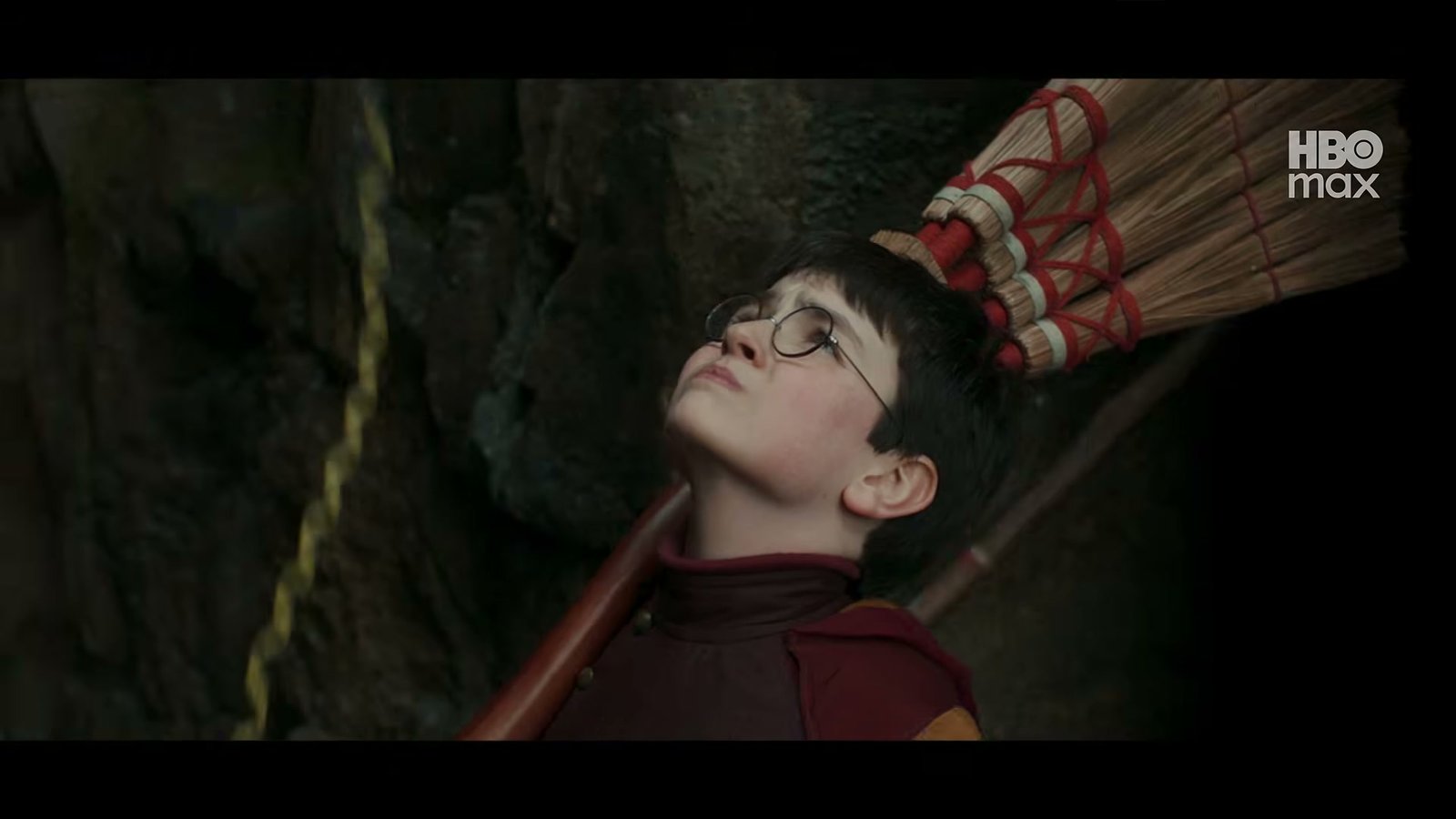 Dominic McLaughlin as Harry Potter in Gryffindor Quidditch robes holding a broom